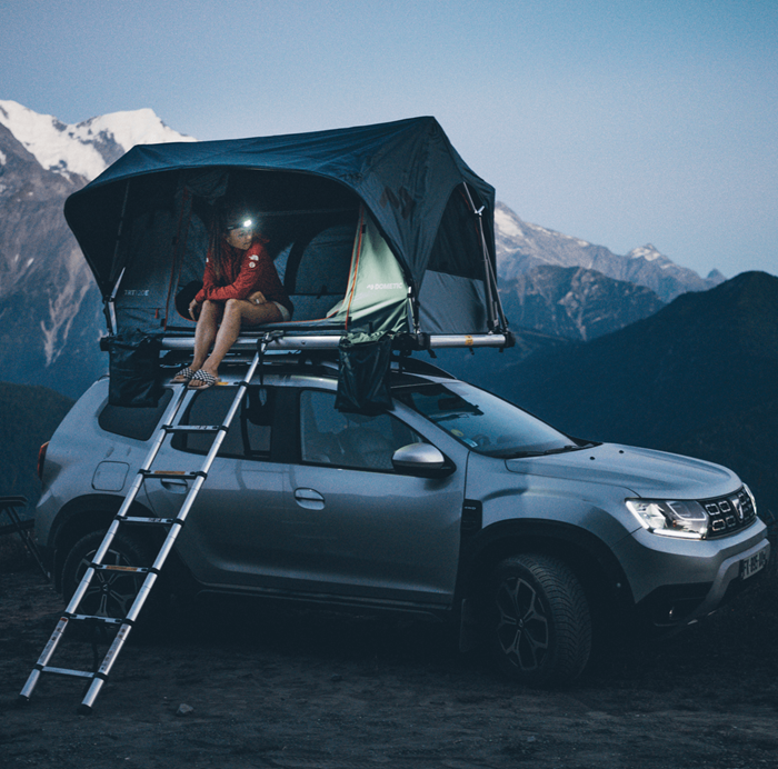 Namiot dachowy na samochodzie terenowym zaparkowanym w górach, nocleg na dachu auta podczas wyprawy outdoorowej