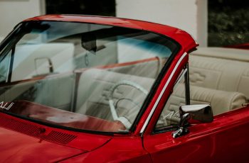 Czerwona szyba samochodowa z widocznym odpryskiem – uszkodzenie szyby czołowej auta