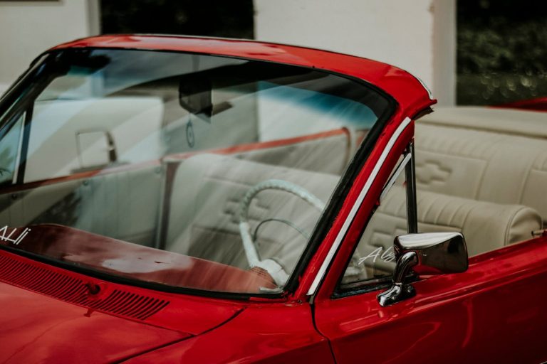 Czerwona szyba samochodowa z widocznym odpryskiem – uszkodzenie szyby czołowej auta