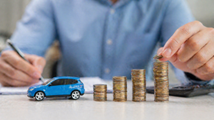 monety i model samochodu symbolizujące oszczędności na ubezpieczeniu OC