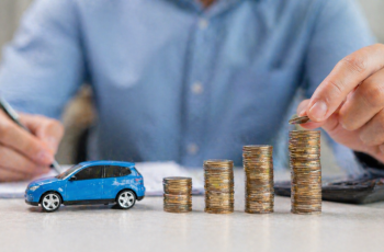 monety i model samochodu symbolizujące oszczędności na ubezpieczeniu OC