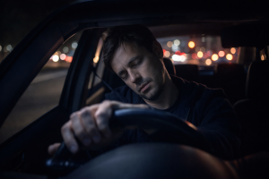 zmęczony kierowca zasypiający za kierownicą nocą